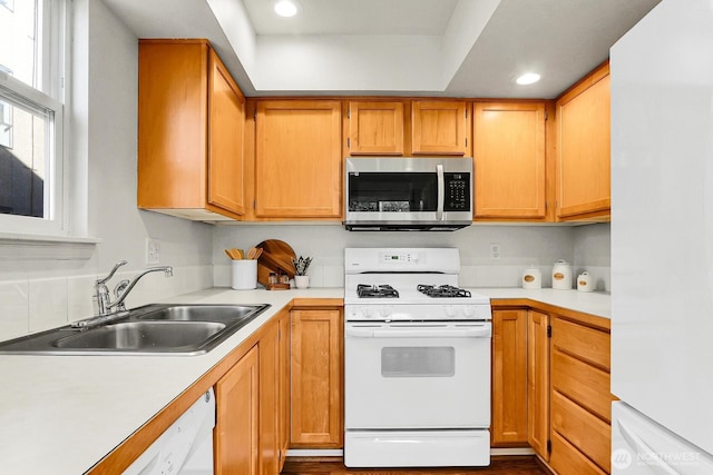 kitchen featuring light countertops, white appliances, a sink, and recessed lighting