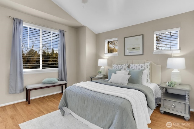 bedroom featuring lofted ceiling, light wood-style floors, multiple windows, and baseboards