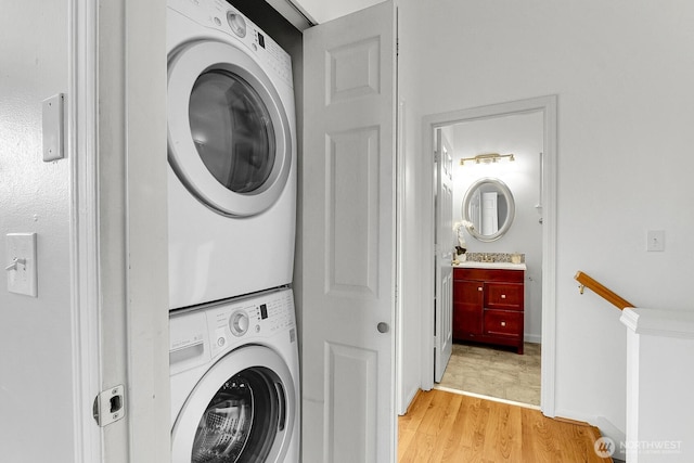 laundry room with light wood-style floors, stacked washer and clothes dryer, and laundry area