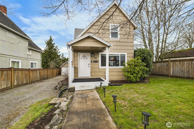 view of front facade with a front lawn, fence private yard, and an outbuilding