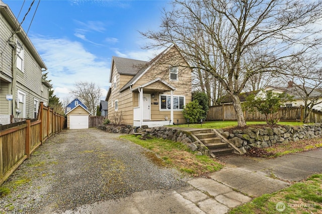 view of front facade featuring a garage, an outdoor structure, driveway, and fence