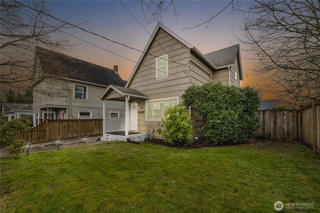 rear view of property featuring a lawn and a fenced backyard