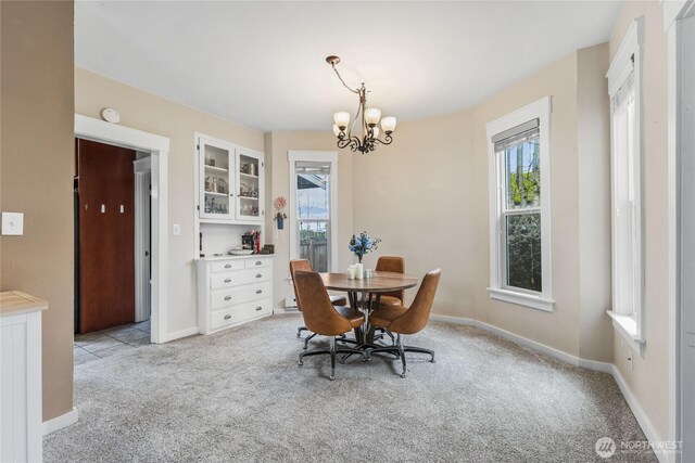 dining area featuring a notable chandelier, plenty of natural light, light colored carpet, and baseboards