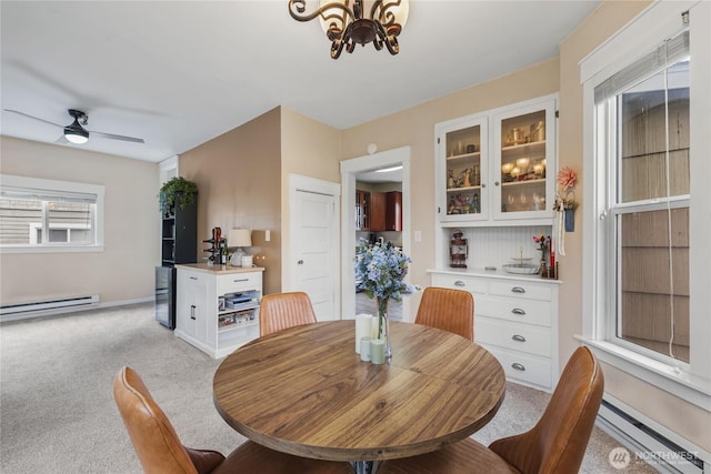 dining space with light carpet, ceiling fan with notable chandelier, and a baseboard heating unit