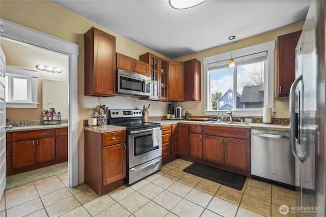 kitchen featuring light tile patterned flooring, a sink, light countertops, glass insert cabinets, and appliances with stainless steel finishes