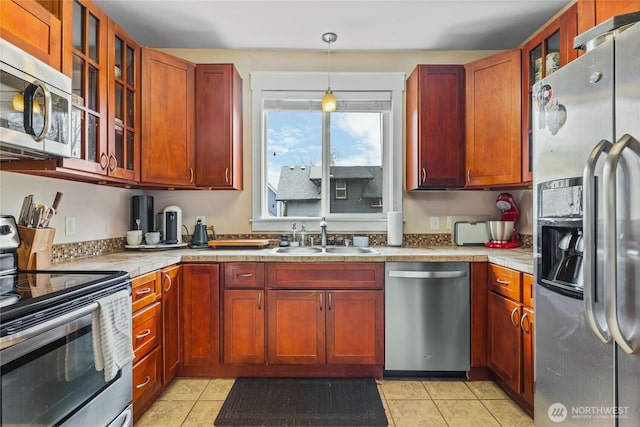 kitchen featuring glass insert cabinets, appliances with stainless steel finishes, light countertops, and a sink