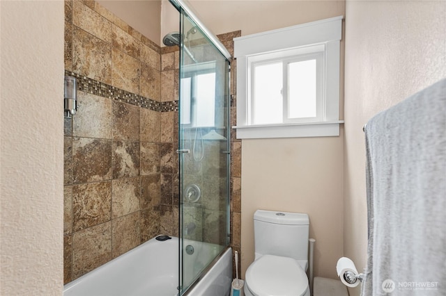 bathroom with combined bath / shower with glass door and toilet