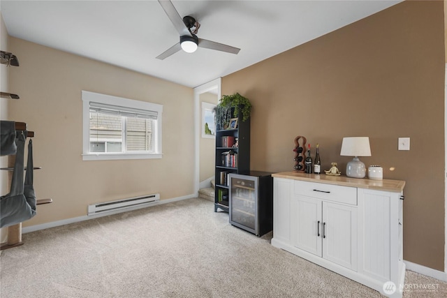 bar with indoor wet bar, light colored carpet, a baseboard heating unit, and a ceiling fan