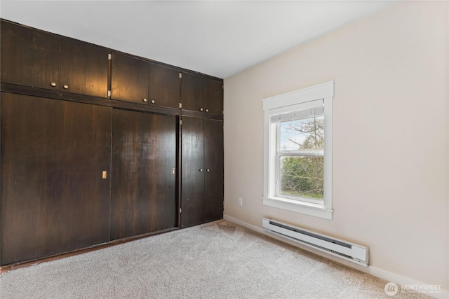 unfurnished bedroom featuring a closet, light colored carpet, a baseboard heating unit, and baseboards