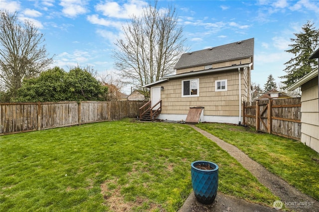 rear view of property featuring a yard, a fenced backyard, and entry steps