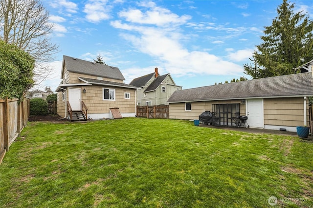 rear view of property with a lawn, entry steps, and a fenced backyard