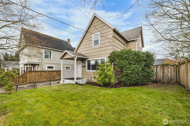 back of house featuring a lawn, roof with shingles, and a fenced backyard