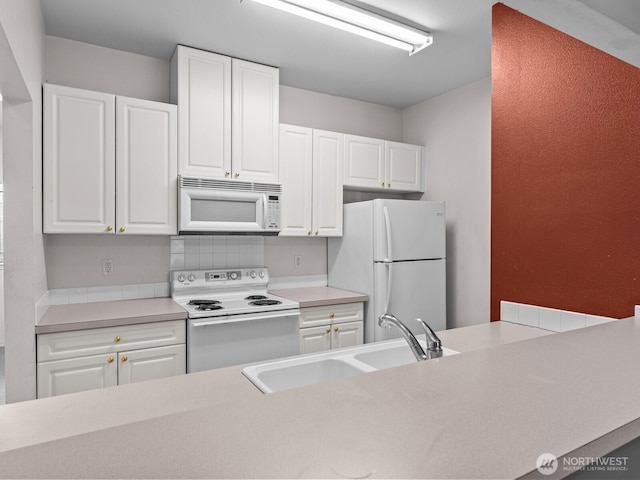 kitchen with white appliances, white cabinetry, light countertops, and a sink