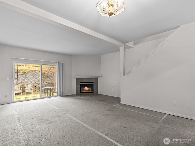 unfurnished living room featuring a tile fireplace, carpet, and an inviting chandelier