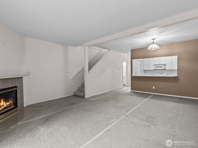 unfurnished living room with stairway, baseboards, and a tile fireplace