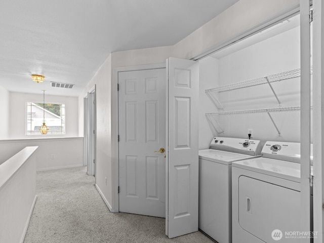 clothes washing area featuring visible vents, baseboards, light colored carpet, laundry area, and washing machine and clothes dryer