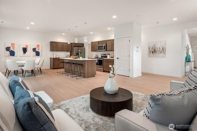 living room featuring recessed lighting, baseboards, and light wood-style flooring