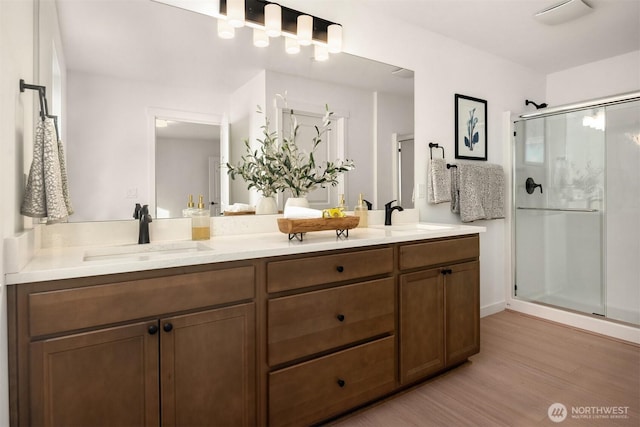 bathroom with a shower stall, wood finished floors, and a sink