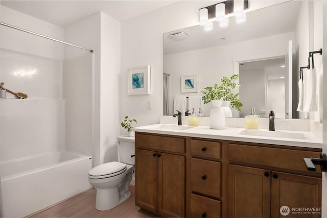 bathroom with double vanity, wood finished floors, toilet, and a sink