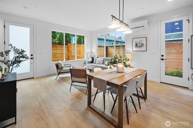 dining room with light wood-type flooring, a wall mounted air conditioner, and baseboards