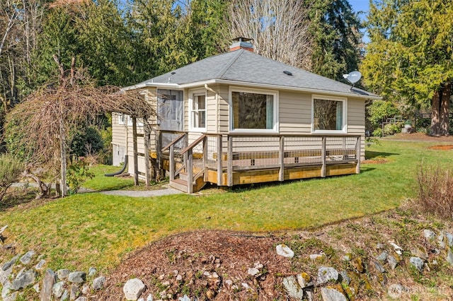 view of front of house with a shingled roof, a chimney, a deck, and a front lawn