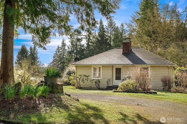 back of property with roof with shingles, a lawn, and a chimney