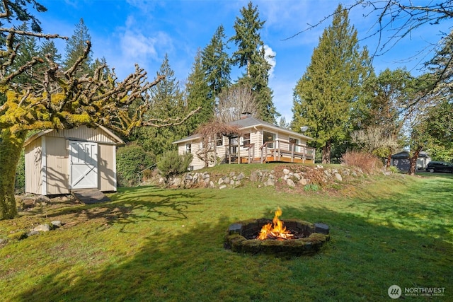 view of yard with an outbuilding, an outdoor fire pit, a wooden deck, and a storage unit