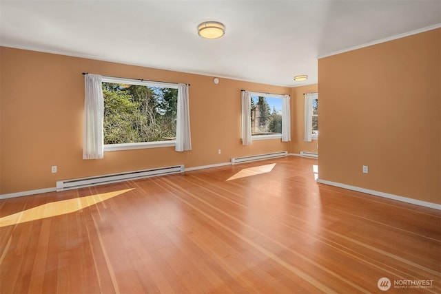 unfurnished room with baseboard heating, wood finished floors, and baseboards