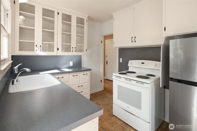 kitchen featuring white electric range oven, white cabinets, ornamental molding, freestanding refrigerator, and a sink