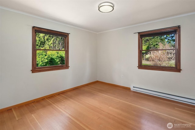 spare room with ornamental molding, light wood finished floors, baseboard heating, and baseboards