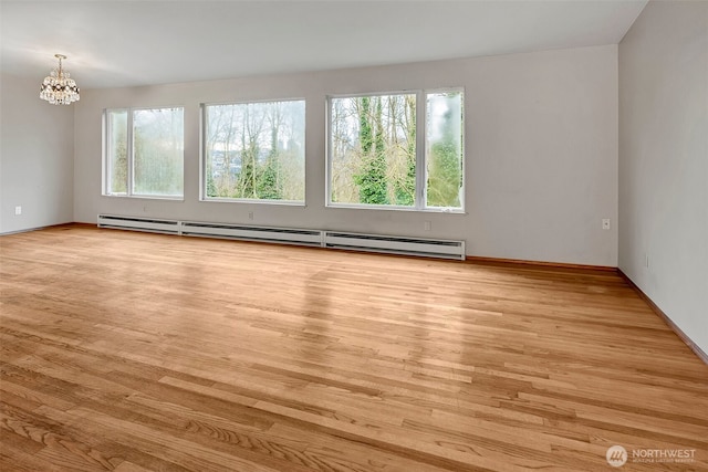 unfurnished room with light wood-type flooring, a baseboard radiator, and an inviting chandelier