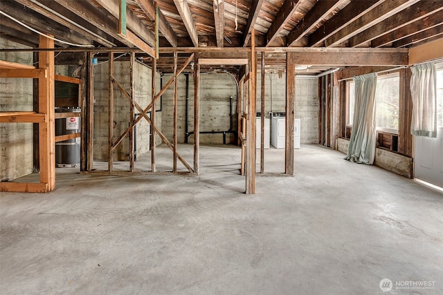 misc room with unfinished concrete flooring, separate washer and dryer, and water heater