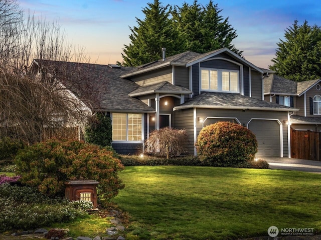 traditional home featuring a garage, a yard, driveway, and fence