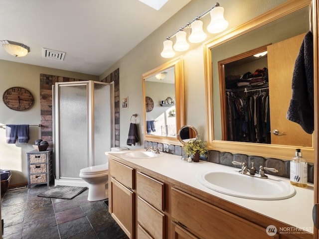 full bath featuring a sink, visible vents, stone tile floors, and a shower stall