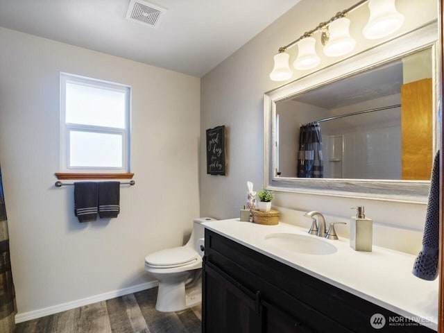 bathroom featuring visible vents, toilet, wood finished floors, baseboards, and vanity