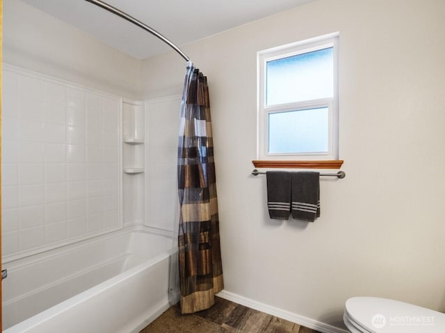 bathroom featuring baseboards, toilet, wood finished floors, and shower / tub combo