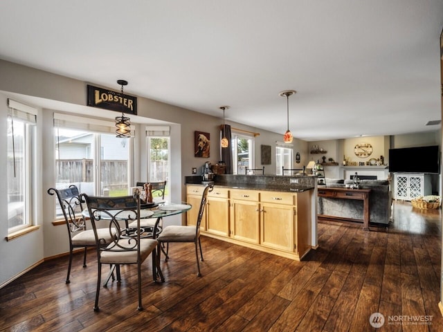 kitchen with dark wood finished floors, dark countertops, light brown cabinets, and pendant lighting