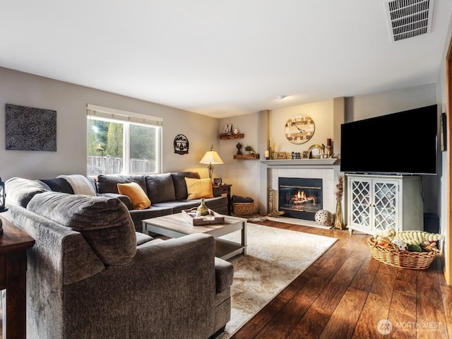 living area with visible vents, a fireplace, and hardwood / wood-style flooring