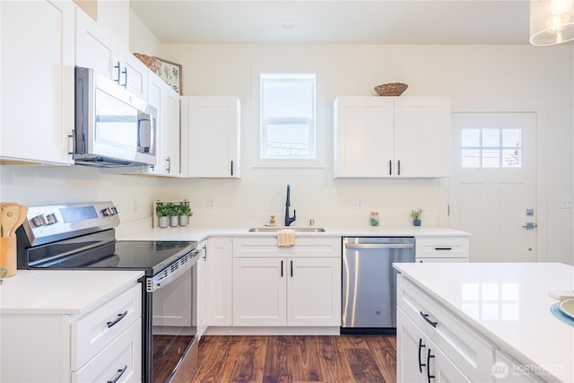 kitchen featuring stainless steel appliances, white cabinets, a sink, and dark wood-style floors