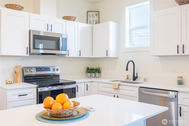 kitchen with light countertops, appliances with stainless steel finishes, a sink, and white cabinetry