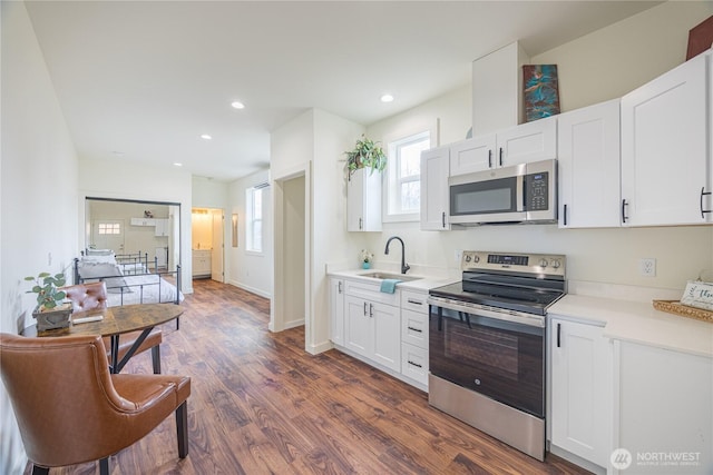 kitchen featuring dark wood finished floors, light countertops, appliances with stainless steel finishes, white cabinets, and a sink