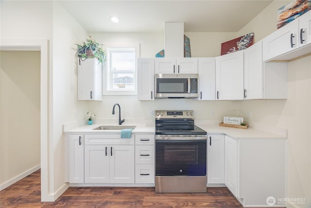 kitchen featuring dark wood-type flooring, stainless steel appliances, a sink, and light countertops