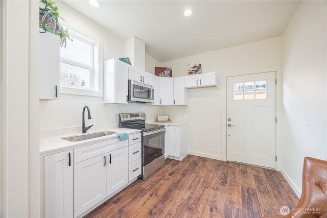 kitchen featuring dark wood finished floors, light countertops, appliances with stainless steel finishes, white cabinetry, and a sink