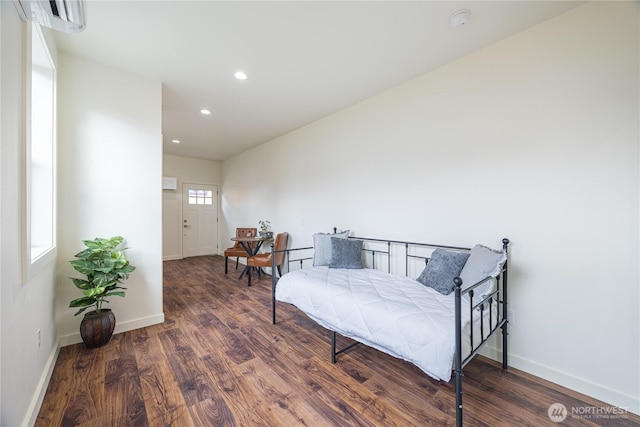 bedroom with recessed lighting, an AC wall unit, baseboards, and wood finished floors