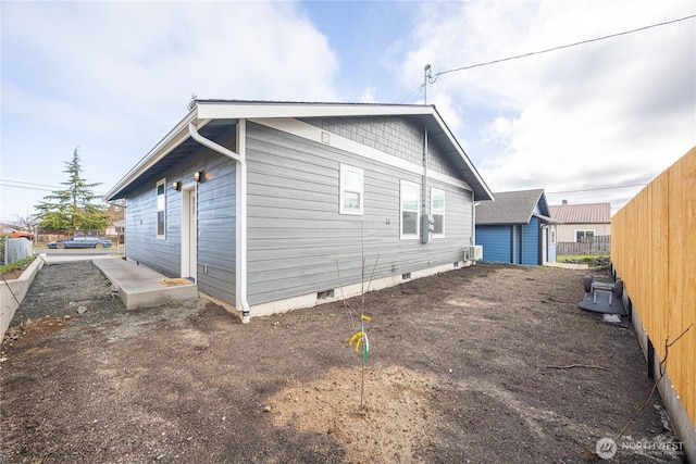 view of side of home with crawl space and fence