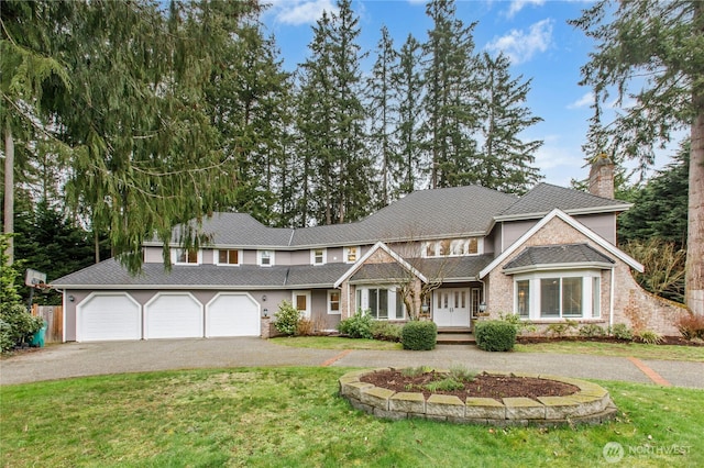 view of front of home with a front yard, driveway, a chimney, and an attached garage