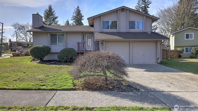 split level home with an attached garage, driveway, roof with shingles, a front lawn, and a chimney