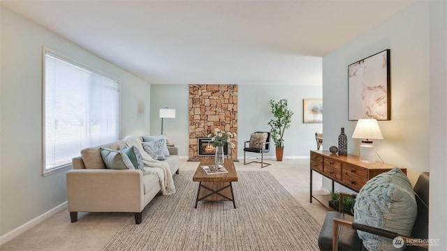 living area featuring carpet, baseboards, and a stone fireplace