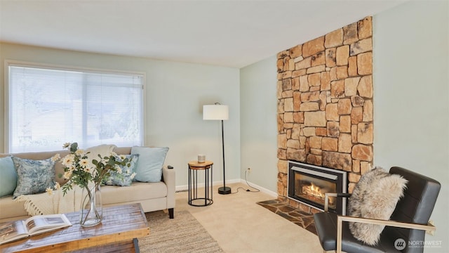 carpeted living room with a stone fireplace and baseboards