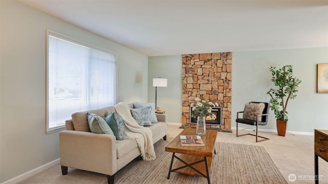 living area featuring carpet, a stone fireplace, and baseboards